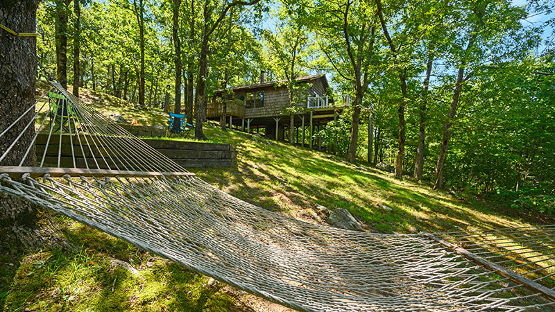 Guests relax in a comfortable hammock or by the fire pit waiting to perch on the patio to view the amazing sunset at Peckerwood Knob Oklahoma Cabins.