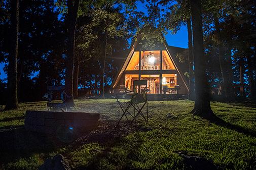 The beautiful a-framed glass front of the Sunrise Cabin at Peckerwood Knob Oklahoma Cabin Rentals at night