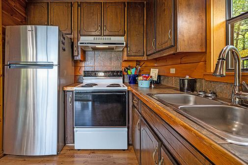 Well-equipped kitchen with stove, refrigerator, dishwasher, microwave, coffeemaker, toaster, pots and pans, dishes, utensils, and silverware at Peckerwood Knob Cabin Rentals in Oklahoma
